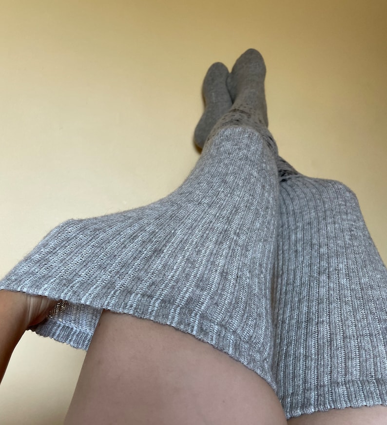 Puede incluir: Un par de calcetines grises de punto acanalado hasta la rodilla. Los calcetines est&aacute;n hechos de un material suave y tienen un aspecto texturizado. Los calcetines est&aacute;n subidos por encima de las rodillas y los muslos.
