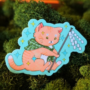 May include: A sticker featuring a cartoon orange cat wearing a green plaid scarf and holding a white flag with a stick. The cat has yellow eyes and a pink nose. The background is a light blue color with yellow and blue stars.