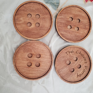 May include: Set of four wooden coasters with a button design. Three coasters have a simple button design, while the fourth coaster has the text "The Chavez Family" engraved on it.