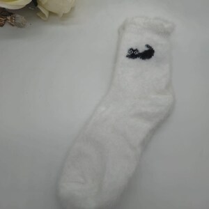 May include: White fuzzy socks with a black cat design.