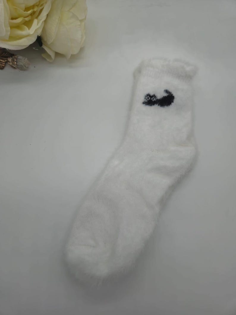 May include: White fuzzy socks with a black cat design.