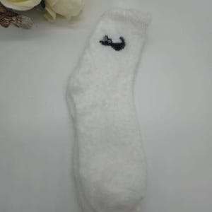 May include: White fuzzy socks with a black cat design on the top.