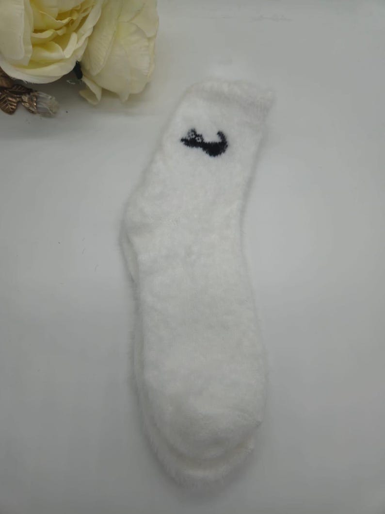 May include: White fuzzy socks with a black cat design on the top.