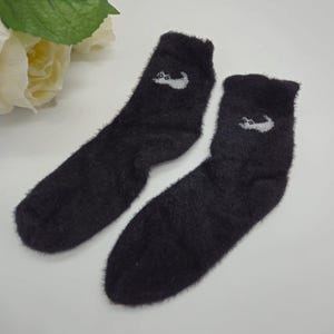 May include: Pair of black fuzzy socks with a white cat design on each sock.