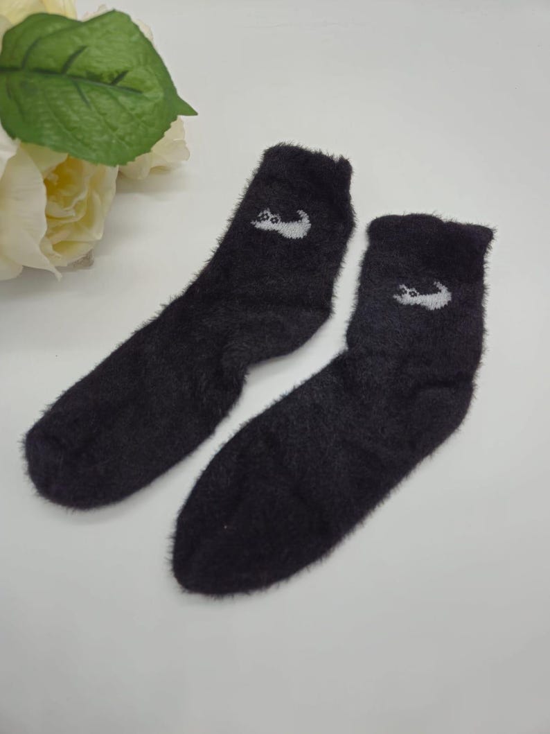 May include: Pair of black fuzzy socks with a white cat design on each sock.