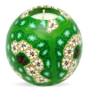 Green sphere candle with floral stained-glass-like designs, glowing from within, featuring cream and brown flowers and a small ladybug accent.