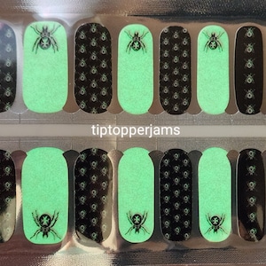 May include: Nail art strips featuring a Halloween theme. The strips alternate between a black spiderweb pattern and a glowing green color. Each strip has a black spider design. The text "tiptopperjams" is visible.