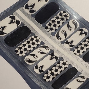 May include: A sheet of black and white nail decals with a soccer ball theme. The decals feature soccer balls, a soccer ball with a swoosh, and a black and white splatter design.