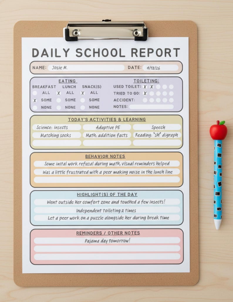 May include: A Daily School Report form on a brown clipboard with a metal clip. The form has sections for eating, toileting, activities, behavior, and notes, with handwritten text including 'Josie M.' and 'Pajama day tomorrow!' next to a blue apple pen.