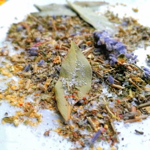 Può includere: Primo piano di un piatto bianco con un mix di erbe secche, spezie e sale. Il mix include foglie di alloro, lavanda e altre erbe.