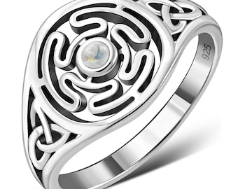 May include: Silver ring with a Celtic knot design and a white gemstone in the center. The ring is marked "925" on the side.