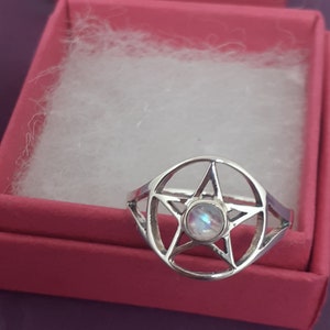 May include: A silver ring with a pentagram design and a moonstone in the center.