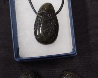 May include: A black gemstone pendant necklace with a teardrop-shaped stone. The necklace is displayed in a blue box with white lining. Two additional teardrop-shaped black gemstones are shown on a black surface.