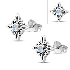 May include: A pair of silver stud earrings. Each earring has a four-pointed star design with a central, round, light blue gemstone. The earrings feature an ornate, swirling pattern and are marked with "925".