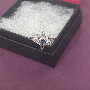 May include: A silver ring featuring a blue gemstone set within a Celtic knot design.