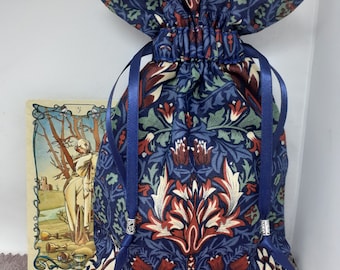 Puede incluir: Una bolsa de tela azul y roja con un diseño floral y cierre de cordón. La bolsa tiene un diseño floral con acentos azules, rojos y blancos. La bolsa es perfecta para guardar objetos pequeños como joyas, cartas de tarot o cristales.