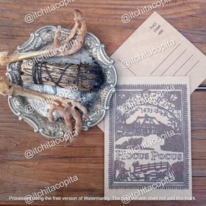 May include: A brown paper postcard with a black and white illustration of a house with the text "Hocus Pocus" and the year "1693". The postcard is on a wooden surface with a silver dish containing a bundle of dried sage and chicken feet.