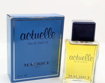 May include: A vintage perfume bottle and box set. The box is blue with gold trim and the words "actuelle" and "MAURICE PARIS" printed on it. The perfume bottle is clear with a black cap and contains a yellow liquid. The bottle is 2 oz.