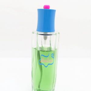 May include: A clear glass perfume bottle filled with green liquid. The bottle has a blue cap with a pink top. The word "Salsa" is written on the bottle in a light blue script.
