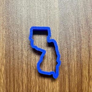 May include: A blue plastic cookie cutter shaped like the state of New Jersey.