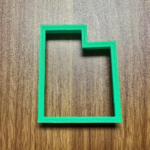 May include: A green plastic cookie cutter shaped like the state of Utah.