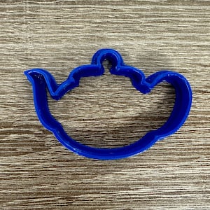 May include: A blue plastic cookie cutter shaped like a teapot.