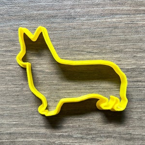 May include: Yellow plastic cookie cutter shaped like a corgi dog.