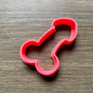 May include: A pink plastic cookie cutter shaped like a human body part.