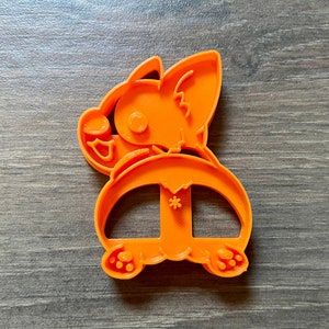 May include: Orange plastic cookie cutter shaped like a cartoon dog with a snowflake on its back.