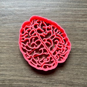 May include: A pink plastic cookie cutter shaped like a human brain.