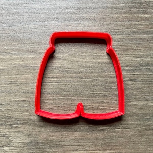 May include: Red plastic cookie cutter shaped like a pair of shorts.