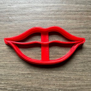 May include: Red plastic cookie cutter shaped like a pair of lips.