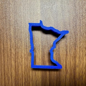 May include: A blue plastic cookie cutter shaped like the state of Minnesota.