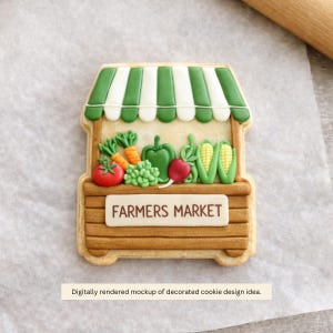 May include: A decorated cookie shaped like a farmer's market stand. The stand is brown with a green and white striped awning. It is filled with colorful cookie vegetables, including tomatoes, carrots, and corn. The sign reads "FARMERS MARKET".