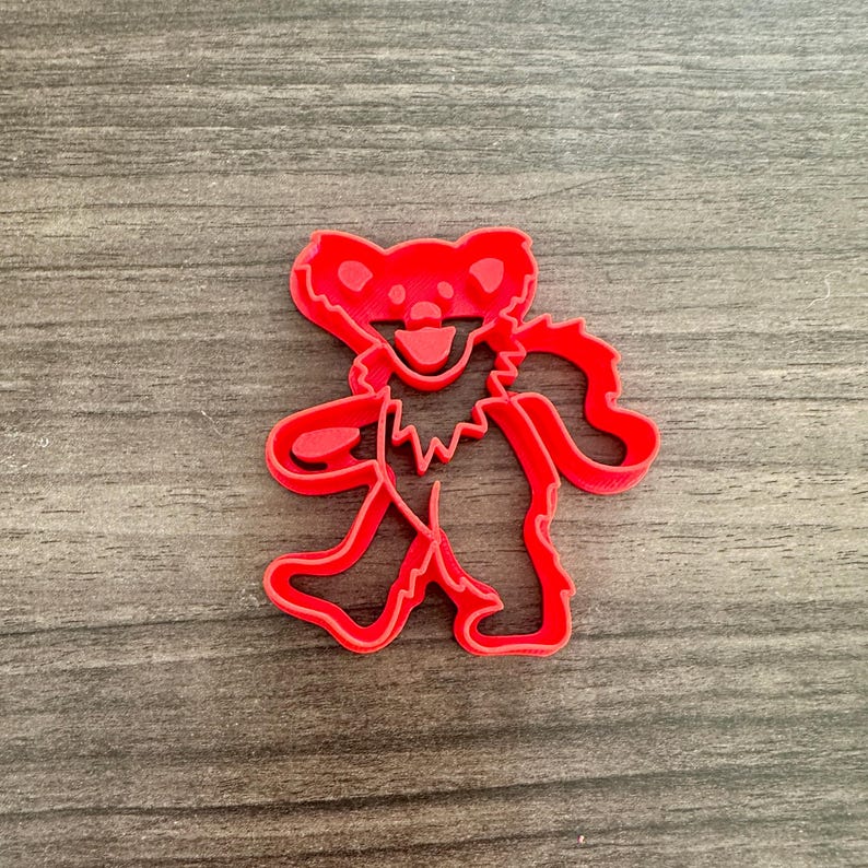 Dancing bear cookie cutter with an outline style, featuring a smiling face and raised arms.