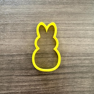 May include: A bright yellow bunny-shaped cookie cutter. The cutter is made of plastic and has a simple, rounded design. The cutter is perfect for making Easter cookies or other treats.