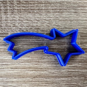 May include: A blue plastic cookie cutter shaped like a shooting star with a five-pointed star at the end.