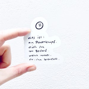 Könnte beinhalten: Ein weißer Aufkleber mit einem schwarzen Pausensymbol und dem Text "dies ist: ein Pausenknopf. druck ihn bei Bedarf. wann immer. du. ihn. brauchst."