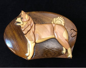 May include: A wooden puzzle box with a detailed carving of a brown and white dog. The box is made of dark wood and has a unique shape.