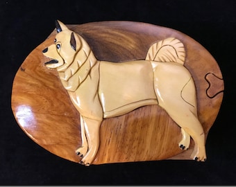 May include: A wooden puzzle box in the shape of a light brown dog. The dog is standing on a wooden base. The puzzle box is made of intricately carved wood.
