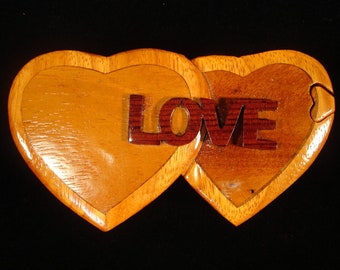 May include: A wooden heart-shaped box with a hinged lid. The box is made of two interlocking hearts, and the word "LOVE" is carved into the top of the box.