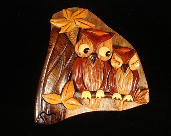 Op de afbeelding: Een houten uil puzzeldoos met twee uilen die in het hout zijn gesneden. De uilen zijn bruin en hebben grote ogen. De doos is driehoekig en heeft een bladerenontwerp aan de bovenkant.