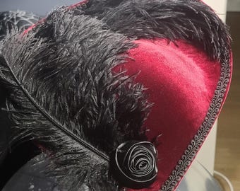 May include: A burgundy velvet pirate hat with a black feather trim and a black velvet rose.
