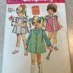 May include: Vintage Simplicity pattern packet, style 8619, featuring illustrations of three young girls in dresses. The packet includes text indicating size 2, breast 21, and child. The price is marked as 65¢.