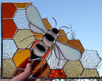 Corner stained glass window-a bee sitting on honeycomb.Stained glass is made in theTiffany technique,the sides are reinforced with a profile