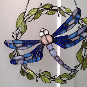 Stained glass wreath with blue dragonfly and green leaves. Window pendant will create a summer atmosphere in your home and garden decor