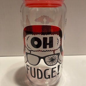 May include: A clear glass tumbler with a red lid and a black and white graphic of a person wearing a Santa hat and glasses with the text "OH FUDGE!" printed on the side.