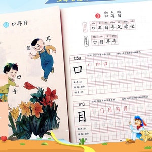May include: An open Chinese language workbook with colorful illustrations and text. The cover reads "First Grade Synchronous Copybook" in Chinese. Inside, pages feature character writing practice with example characters and stroke order guides.