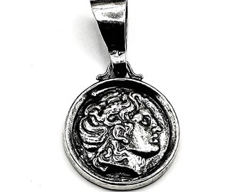 Op de afbeelding: Zilveren hanger met een gedetailleerd profiel van een Griekse god of godin. De hanger is rond en heeft een lus om aan een ketting te bevestigen.