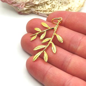 May include: Gold-toned olive branch pendant charm with a textured finish. The charm has a loop at the top for attaching to a necklace or bracelet.